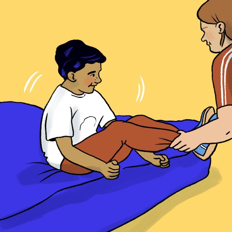 Illustration av ett barn som sitter på en blå madrass med böjda ben och håller runt sina knän. En vuxen person håller i barnets fötter och rullar försiktigt fram och tillbaka så att barnet gungar. Barnet bär vit t-shirt och röda byxor och ser glatt ut. Bakgrunden är gul.